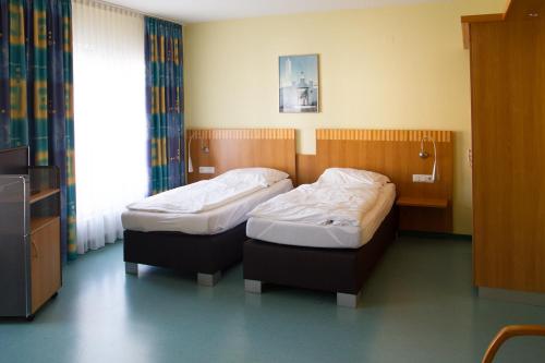 two twin beds in a hospital room with a window at Hotel Restaurant Warndtperle in Völklingen