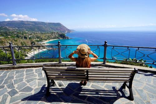 a person sitting on a bench looking at the ocean at Astra Solea in Capo Vaticano