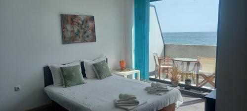 a bedroom with a bed and a balcony with the ocean at Azur Apartments in Sozopol