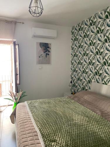 a bedroom with a bed with a green patterned wall at Xenia Rooms in Salemi