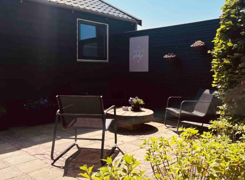 a patio with two chairs and a table at B&B de Lytse Geast in Tietjerk
