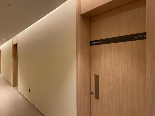 a hallway with wooden doors in a building at 1 Bedroom Apartment at Marassi Vista Residence in Muharraq