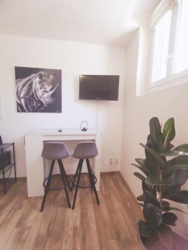 - un bureau et deux tabourets dans une pièce avec une plante dans l'établissement Charmant studio, cœurdeSouillac tidordognehomes, à Souillac