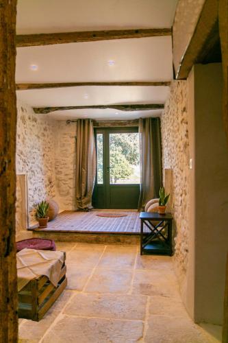 - une chambre avec une grande fenêtre dans un mur en pierre dans l'établissement Gîte Mas de Boulègue, à Saint-Pantaléon-les-Vignes