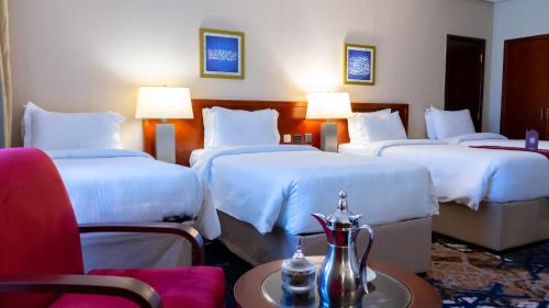a hotel room with three beds and a table and chairs at فندق الصفوة البرج الثالث Al Safwah Hotel Third Tower 3 in Makkah