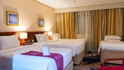 a hotel room with three beds and two tables at فندق الصفوة البرج الثالث Al Safwah Hotel Third Tower 3 in Makkah