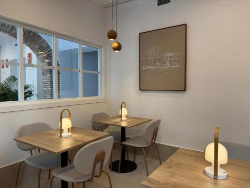 two tables and chairs in a room with a window at La Caleta QE Hotels in Cádiz