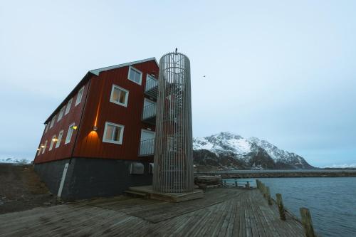 a building on a dock next to a body of water at Skata Hotel Henningsvær in Henningsvær
