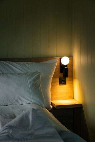 a bed with a lamp on a night stand next to it at Skata Hotel Henningsvær in Henningsvær