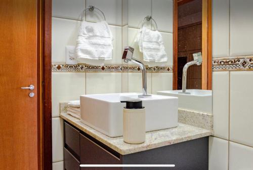 a bathroom with a white sink and two mirrors at LOFT no Centro de Campos Novos in Campos Novos