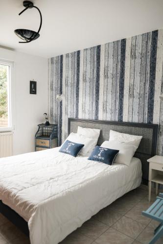 une chambre avec un grand lit blanc avec des oreillers bleus dans l'établissement Evasion familiale à la plage, à Trégastel