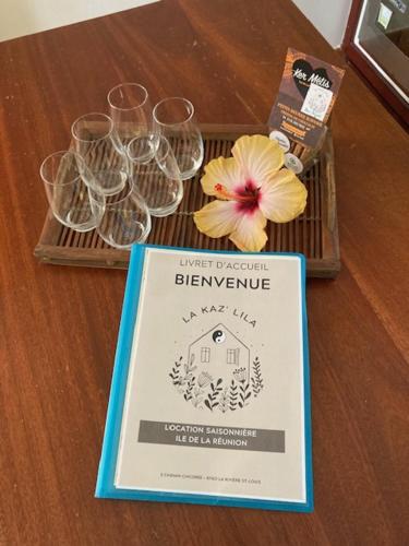 a sign on a table with glasses and a flower at La Kaz' Lila - Villa avec piscine - Jardin 1000m2 in Saint-Louis