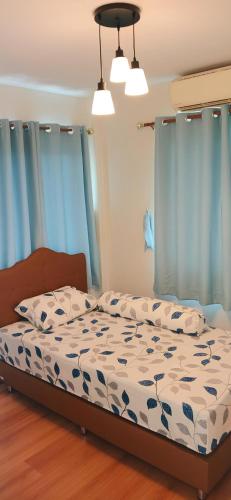 a bed in a bedroom with blue curtains at Pailin Hill At Casa Ville Watcharapol in Bangkok