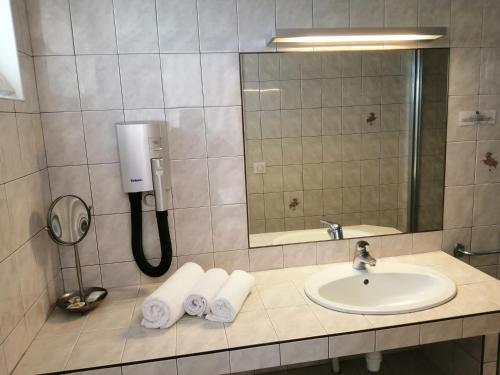 a bathroom with a sink and a mirror and towels at Hôtel Les Fleurs in Pontaubert