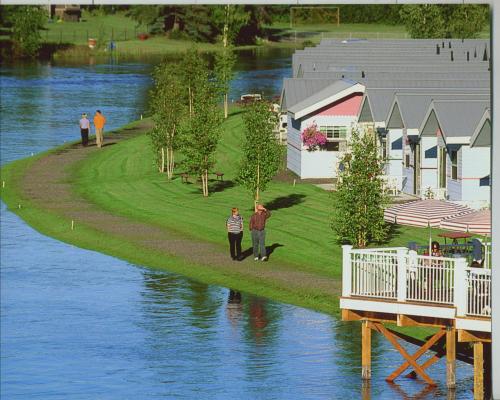 a man standing on a lawn next to a body of water at River's Edge Resort in Fairbanks