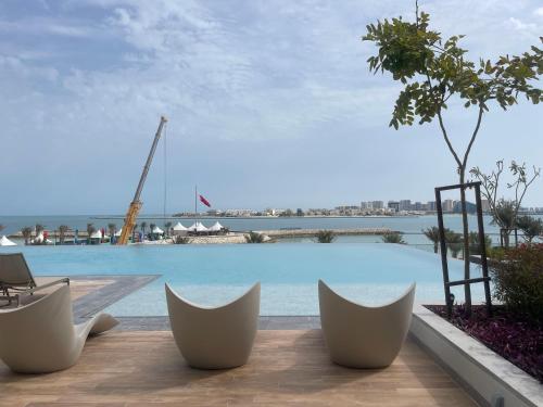 a view of a swimming pool with chairs in front of it at 1 Bedroom Apartment at Marassi Vista Residence in Muharraq