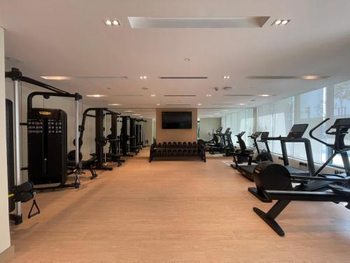 a gym with a row of treadmills and machines at 1 Bedroom Apartment at Marassi Vista Residence in Muharraq