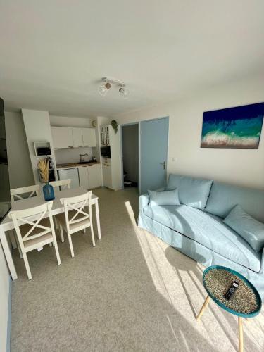 un salon avec un canapé bleu et une table dans l'établissement Appartement 250m mer, 2 vélos avec casques, entièrement rénové en 2025, à Cabourg