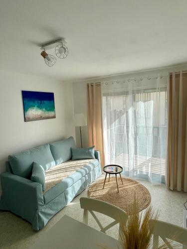 un salon avec un canapé bleu et une table dans l'établissement Appartement 250m mer, 2 vélos avec casques, entièrement rénové en 2025, à Cabourg