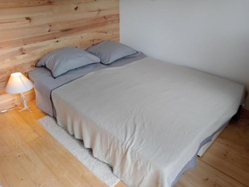 Cette chambre comprend un lit avec deux oreillers et une lampe. dans l'établissement Tiny house sous le chene, à Saint-Roch