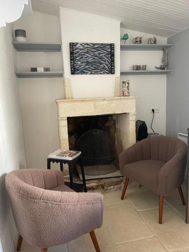 a living room with two chairs and a fireplace at une fenêtre sur cour in La Flotte