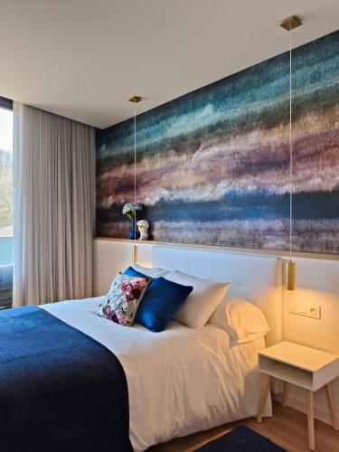 a bedroom with a bed with a painting on the wall at Apartamento Hortensia Diseño Exclusivo in Ponteareas