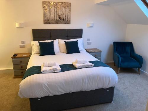 ein Schlafzimmer mit einem großen Bett und einem blauen Stuhl in der Unterkunft Hideaway Cottage in Troedyraur