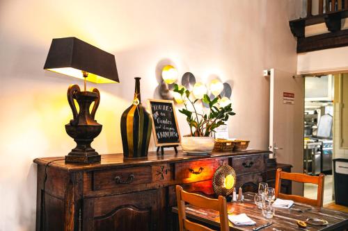 a table with a lamp on top of a wooden dresser at Logis Hôtel et Restaurant La Bombardière in Cuq-Toulza
