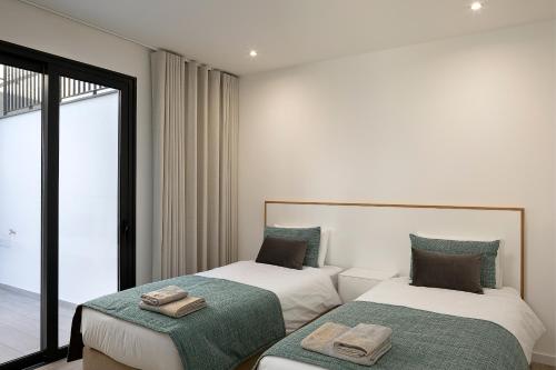 two beds in a room with a window at Marco 4 Seasons- Winter in Arco da Calheta