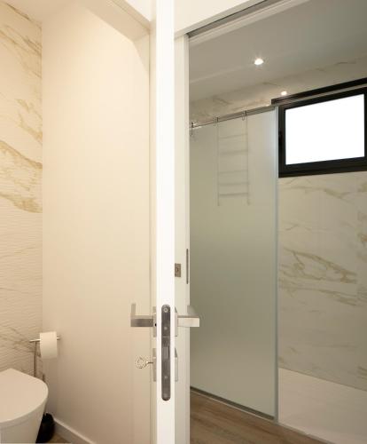 a bathroom with a toilet and a glass shower door at Marco 4 Seasons- Winter in Arco da Calheta