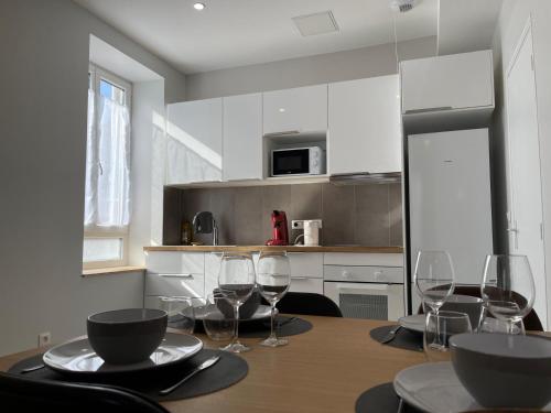 une cuisine avec une table avec des verres à vin dessus dans l'établissement Appart'Village Le vieux Vichy centre T1,T2,T3 - Parking - Thermes, à Vichy