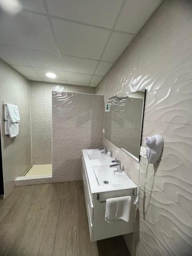 a bathroom with a sink and a mirror and a shower at Hotel Restaurante Dama de Baza in Baza