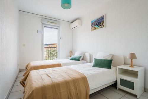 deux lits dans une chambre blanche avec une fenêtre dans l'établissement EVASION T3 lumineux avec parking et clim, à La Ciotat