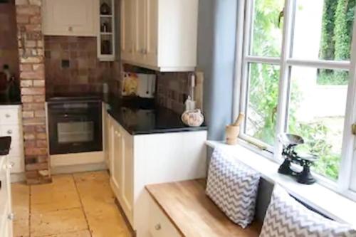 a kitchen with white cabinets and a large window at 5-Bed Home - Sleeps 12 Pool Garden & Play Area in Taunton