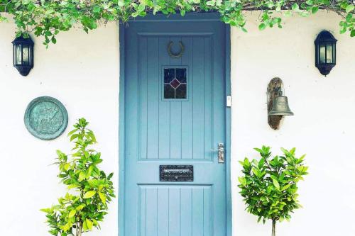 a blue door on a white house with a bell at 5-Bed Home - Sleeps 12 Pool Garden & Play Area in Taunton