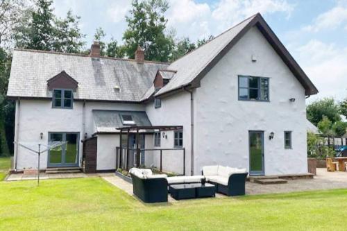 a white house with two couches in a yard at 5-Bed Home - Sleeps 12 Pool Garden & Play Area in Taunton