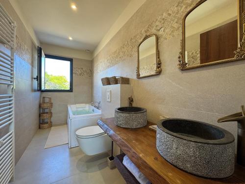 une salle de bain avec un lavabo, des toilettes et un miroir dans l'établissement Villa de standing avec piscine et jacuzzi, à Belgodère