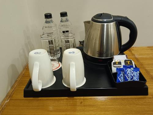 a black tray with two cups and a tea pot and water bottles at Hotel Prag Continental in Guwahati