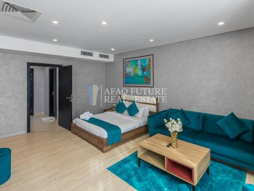 a living room with a blue couch and a bed at Vita Tower in Manama