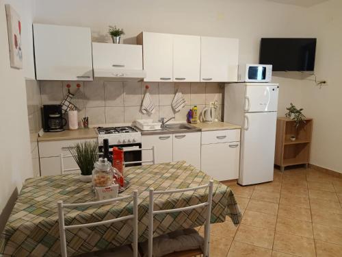 a small kitchen with a table and a white refrigerator at Apartmani Goga Tomić in Seline