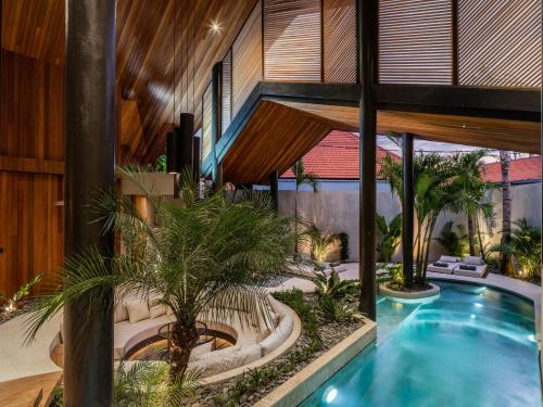 una piscina cubierta en una casa con palmeras en Villa Levante Bali by House of Winds - Tropical Oasis near Canggu, en Kerobokan