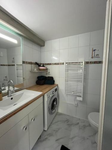 une salle de bain avec une machine à laver et un lavabo dans l'établissement Appartement proche plage et centre ville, à La Rochelle