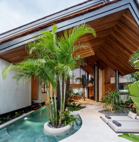 an indoor pool with palm trees in front of a house at Villa Levante Bali by House of Winds - Tropical Oasis near Canggu in Kerobokan