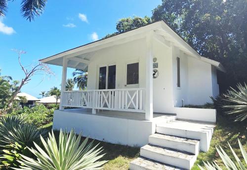 a small white house with stairs in a yard at El Pelicano Apart-Hotel in Las Galeras