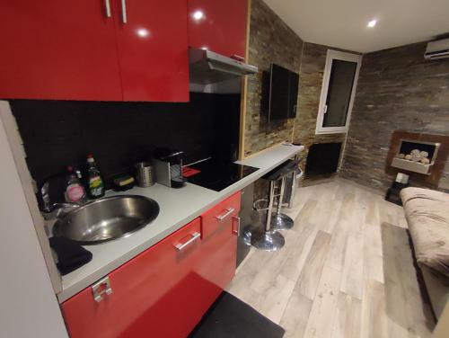 - une cuisine avec des placards rouges et un évier dans la chambre dans l'établissement Studio les 2 Alpes au Village 1800m-Commerces et télésiège à 50m-Retour ski au pied, à Les Deux Alpes