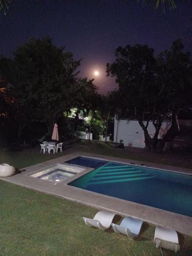 a swimming pool at night with chairs and a table at Quinta las flores de Elizondo in Xochitepec