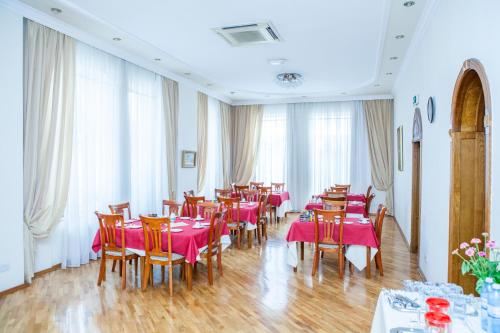a restaurant with tables and chairs with pink tablecloths at Azcot Hotel in Baku