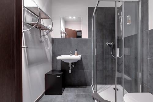a bathroom with a glass shower and a sink at VV hotel & apartments in Brno
