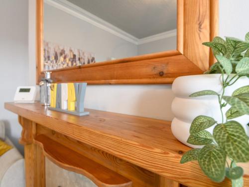 a wooden table with a mirror and a plant on it at Pass the Keys Brighouse Central - Ideal For Workers in Brighouse