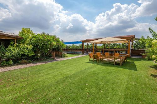 a patio with a table and chairs on a lawn at בקתות רם-מתחם בקתות מהמם עם בריכה פרטית ונוף מושלם in Sede Terumot